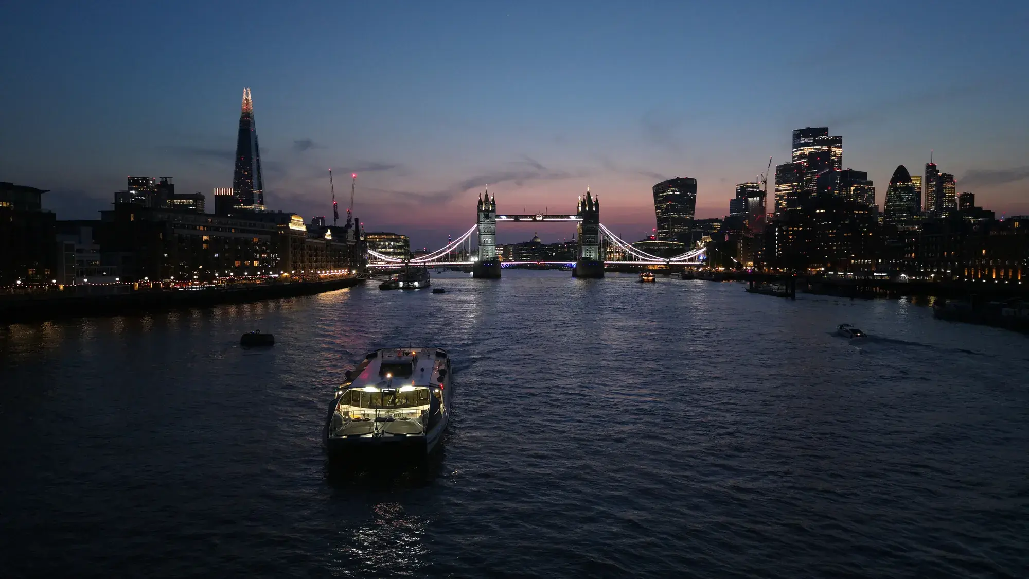 Blue hour aerial photograph of Tower Bridge and the illuminated City of London skyline