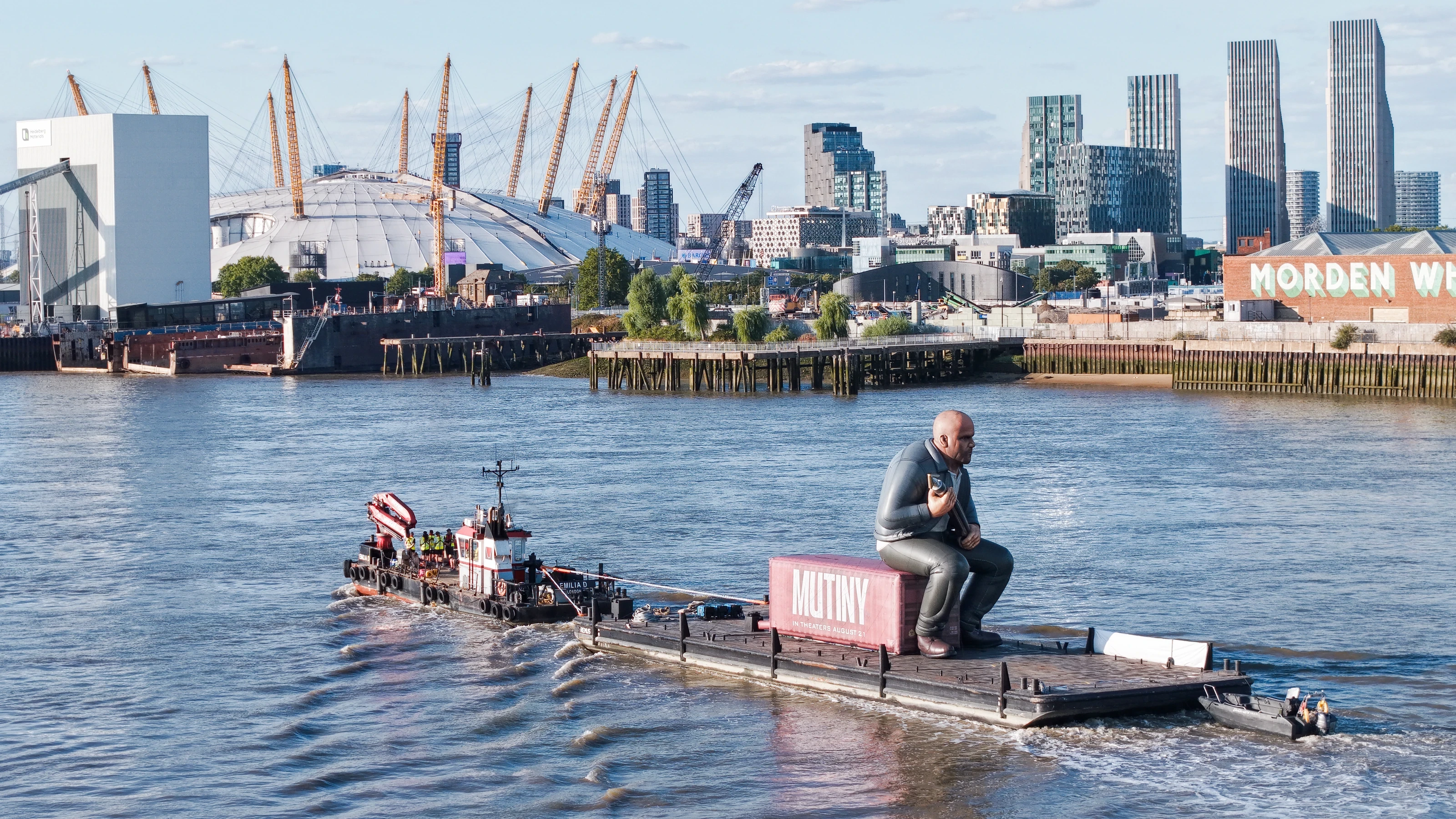 Close aerial photograph of the Mutiny shipping container marked 'In theaters August 21' with the giant Jason Statham inflatable seated on top.