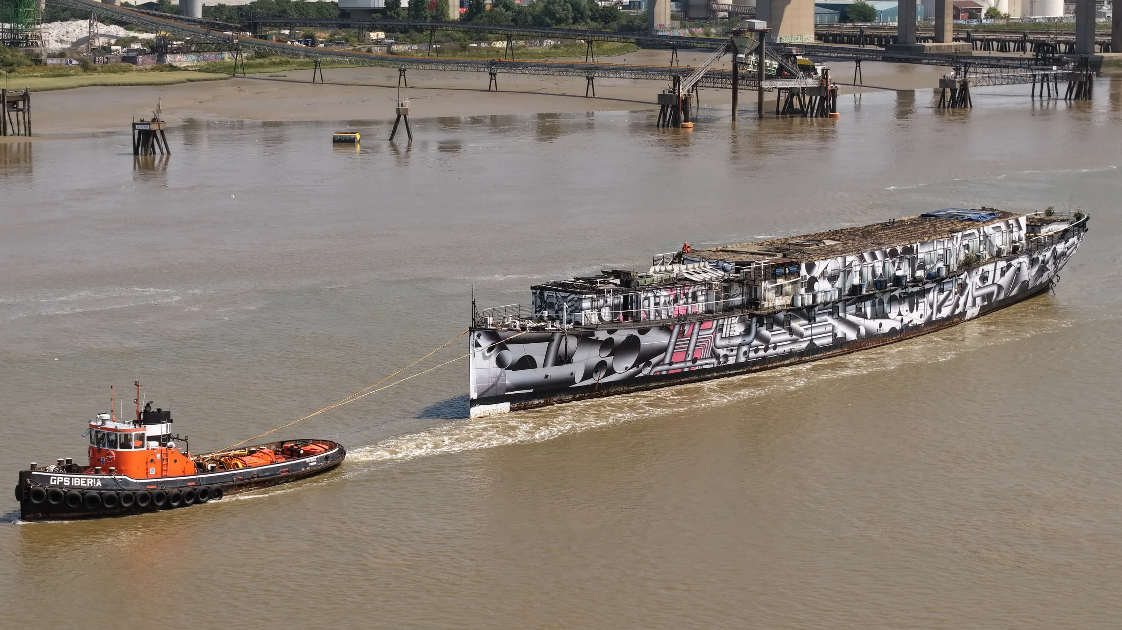 Aerial photograph of HMS President 1918 under tow on the Thames with both GPS Marine tugs working the vessel.