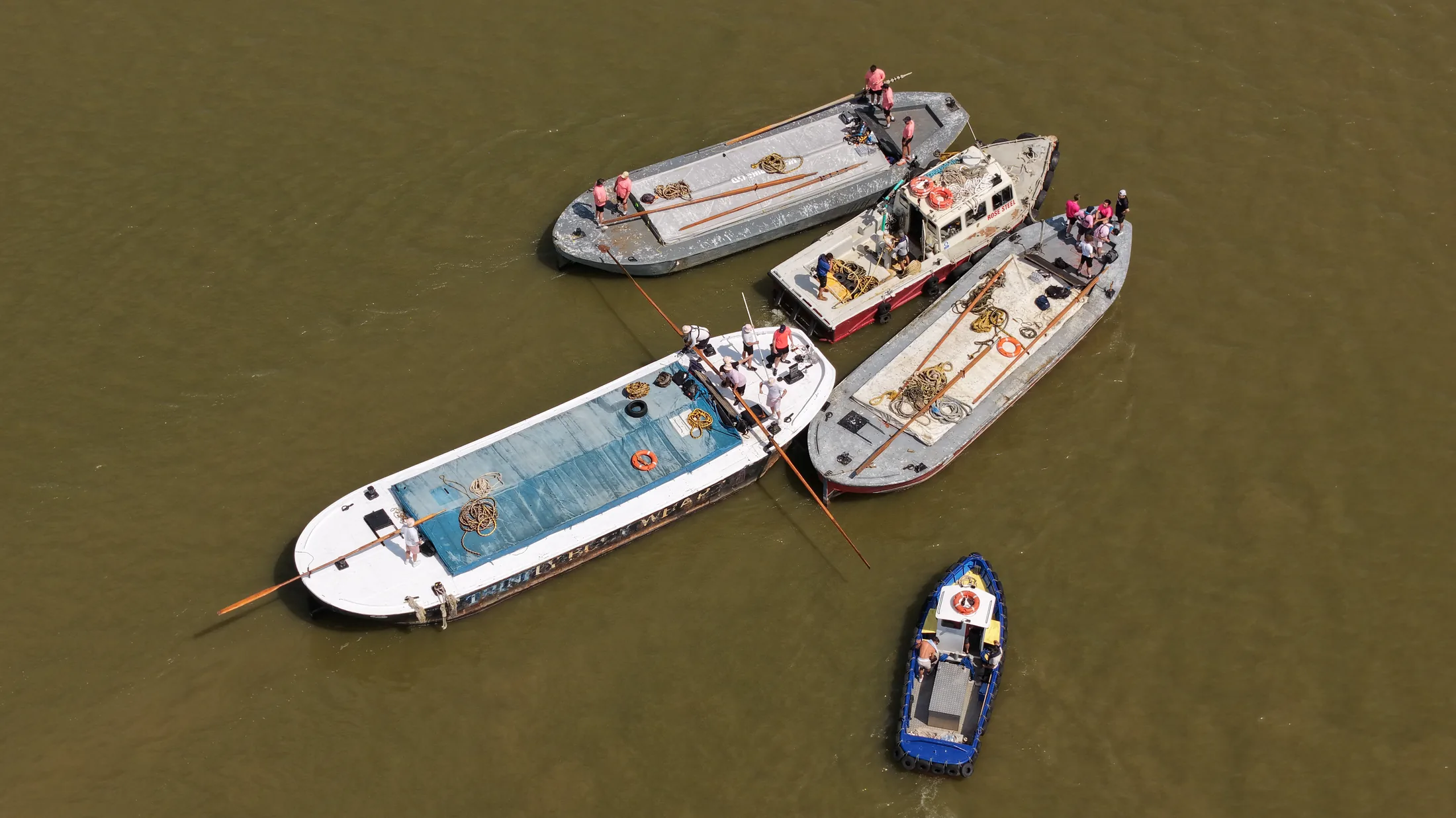 Aerial photograph looking down on Thames barges rafted together and moored before the start of the race, with crews and small craft alongside.