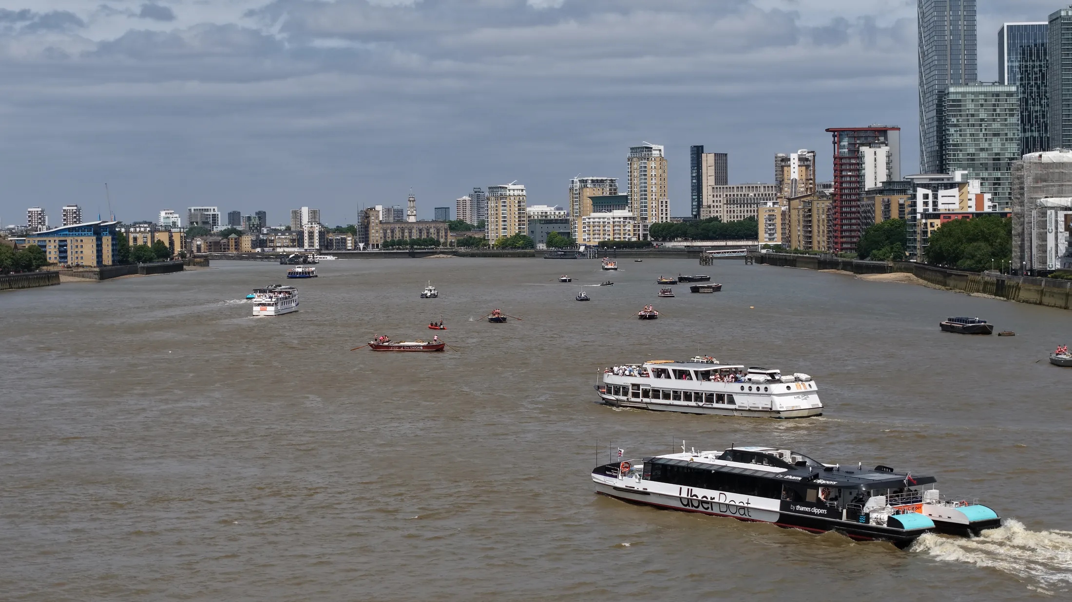 Aerial photograph of the River Thames at Limehouse Reach showing choppy water, racing barges spread across the river and passenger vessels under way between them.