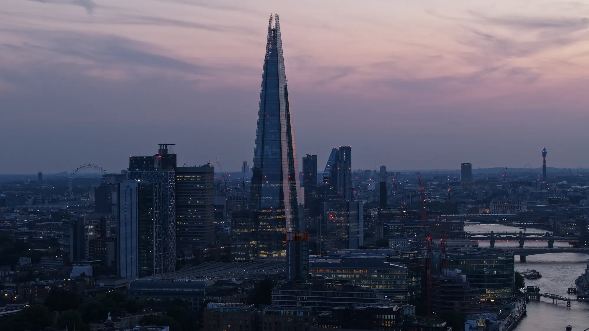 Aerial drone photograph of the City of London skyline and construction cranes at twilight