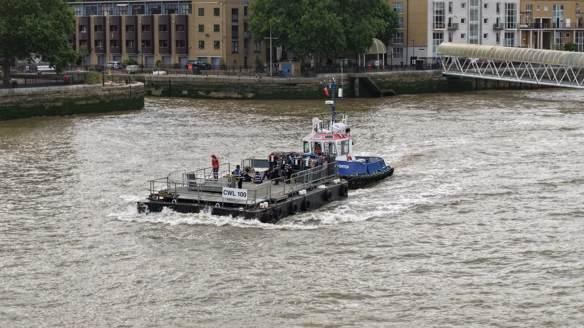 Aerial photograph of a workboat on the River Thames beside London riverside wharves