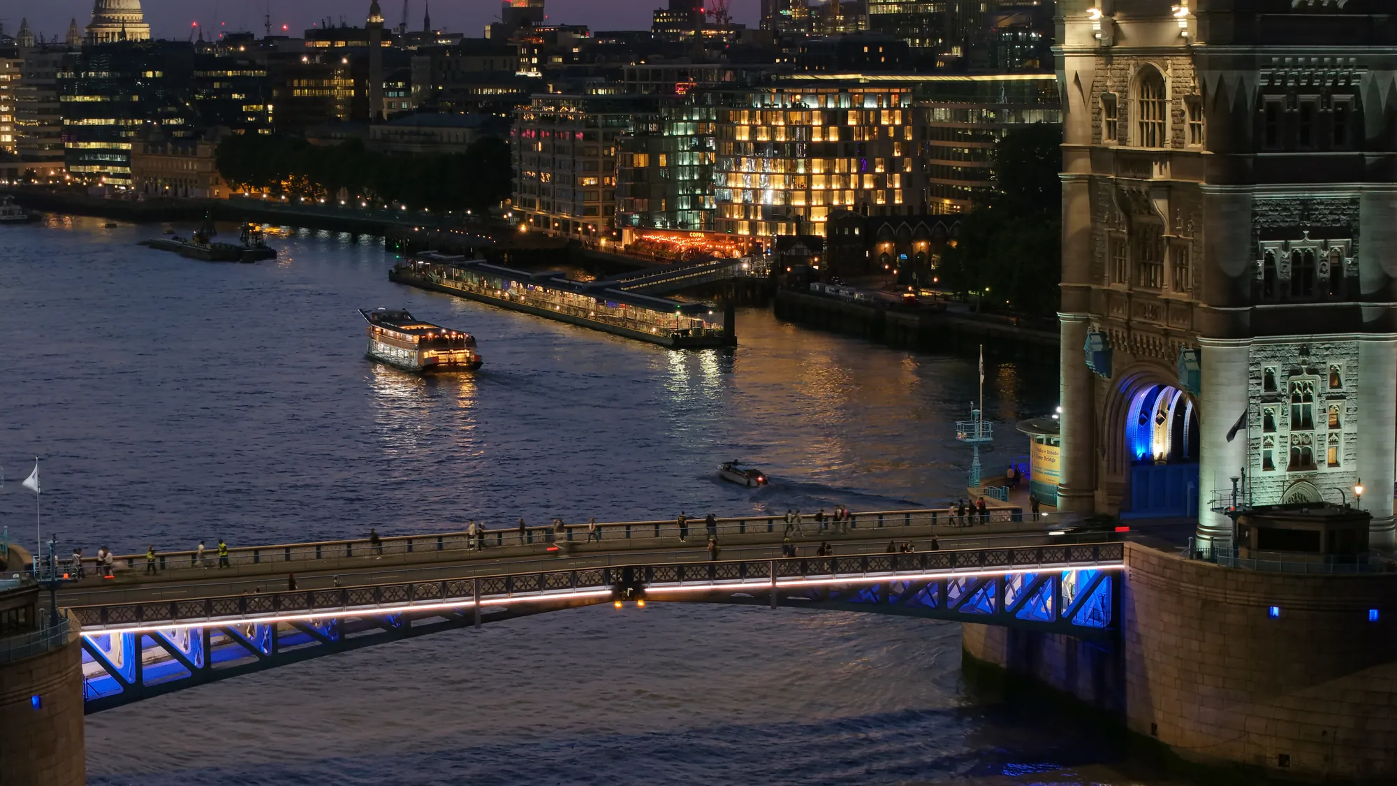 Night aerial drone shot of Tower Bridge illuminated in blue over the River Thames in London