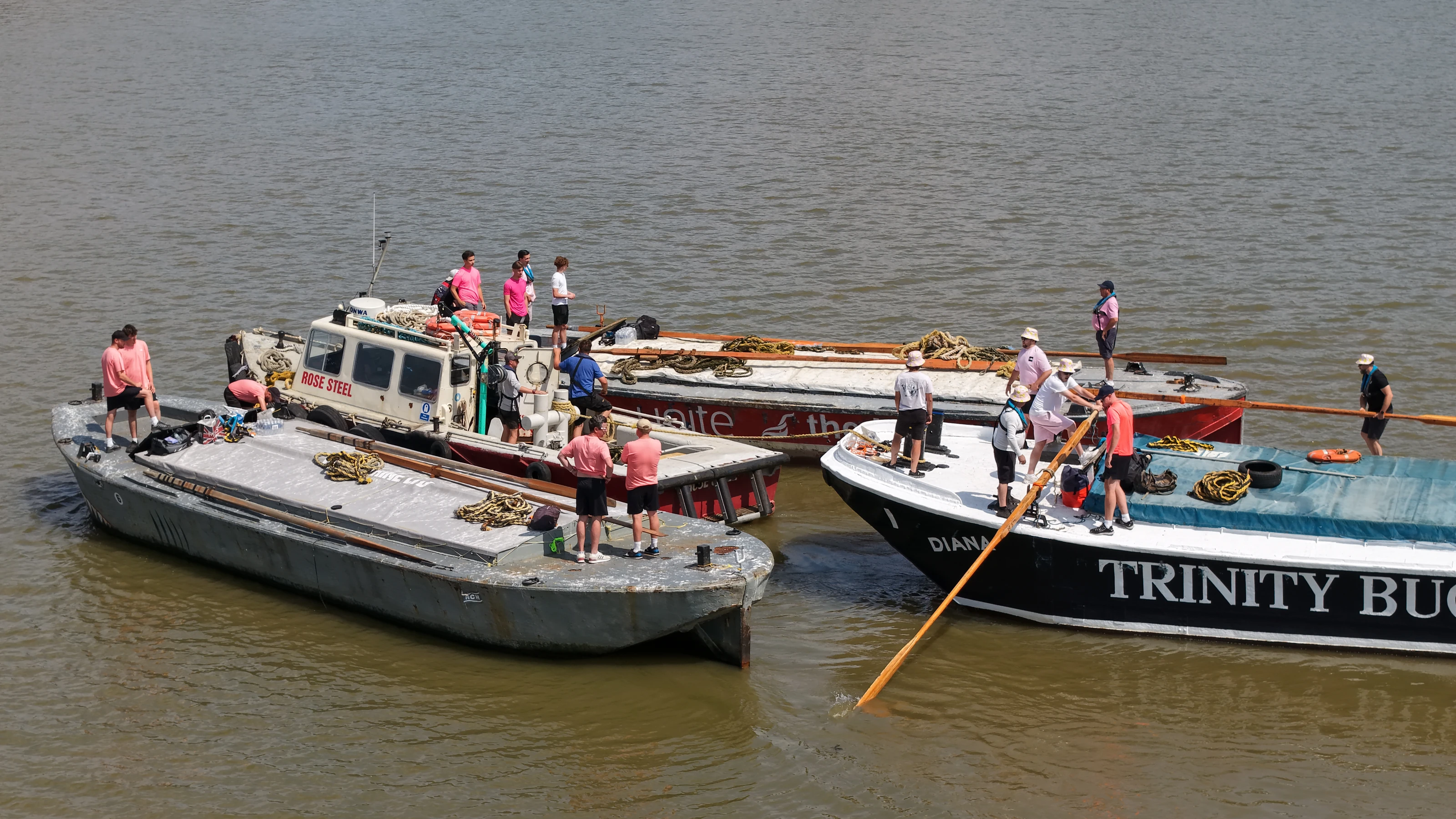 Crews aboard the Trinity Buoy Wharf barge before the start of the Thames barge driving race, an oar run out over the side