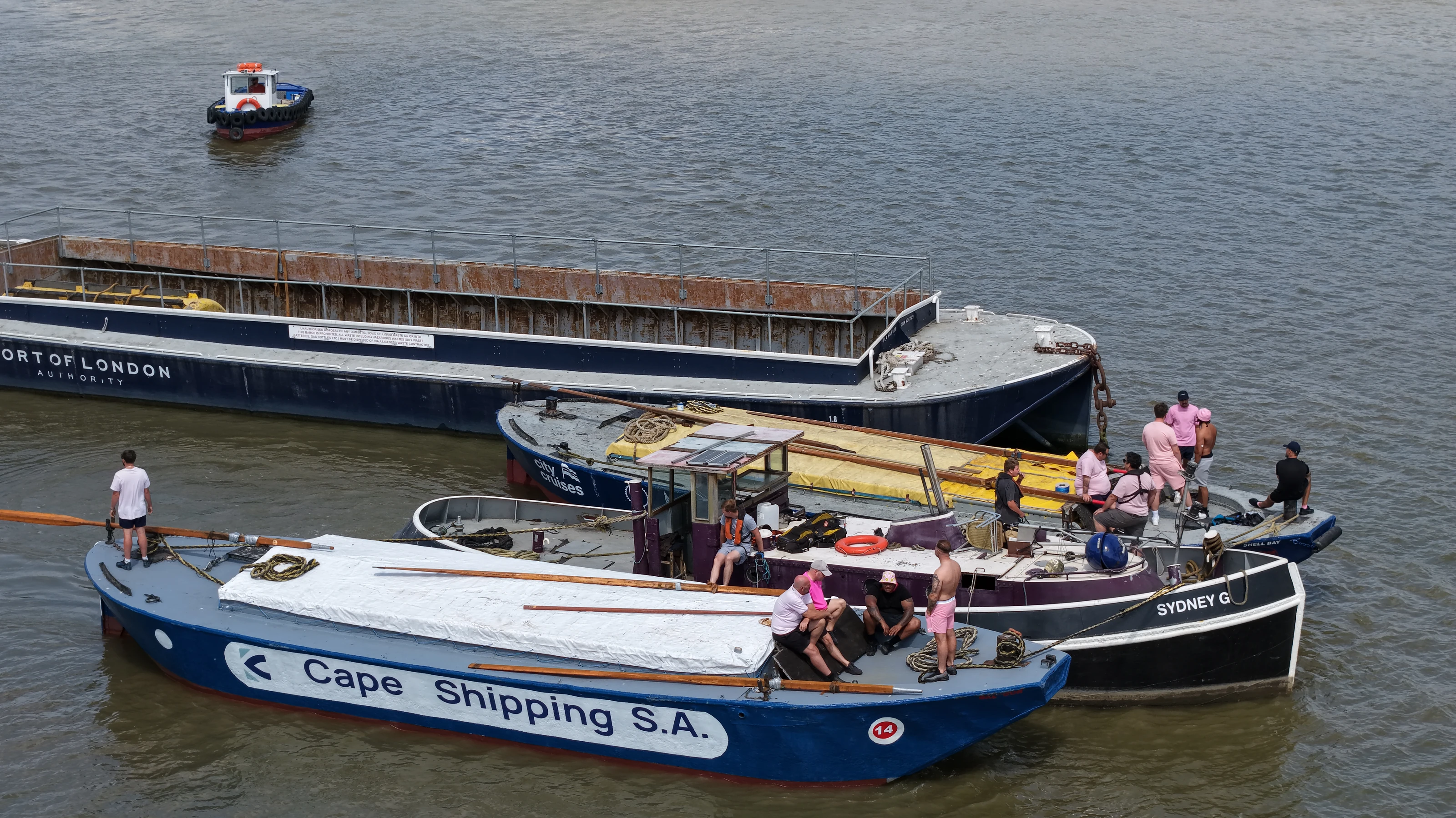 Barges lettered for the Port of London Authority and Cape Shipping S.A. rafted together with their crews before the race