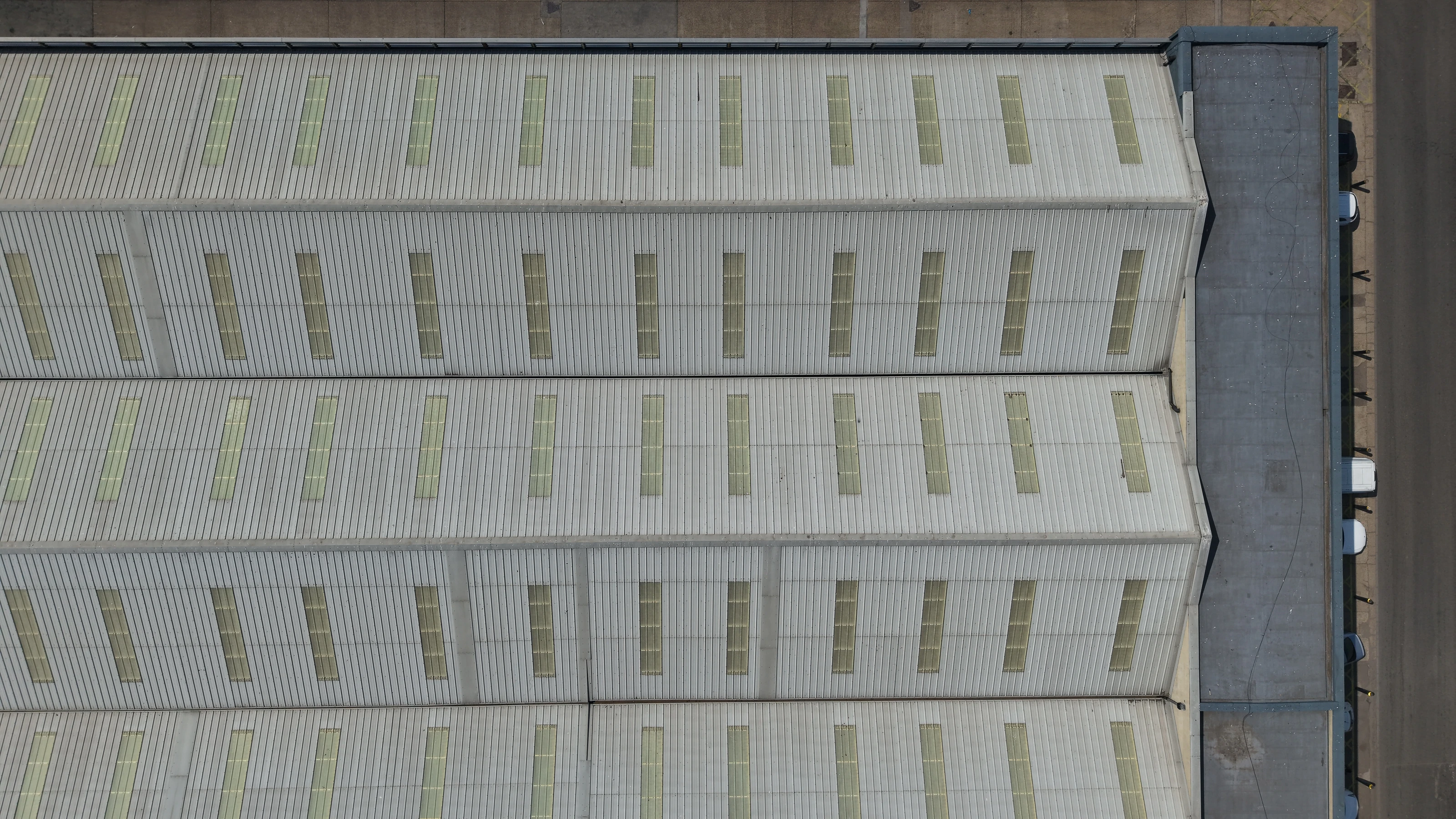 Close aerial detail of rooflight panels on a commercial roof, showing yellowing and staining across the sheets