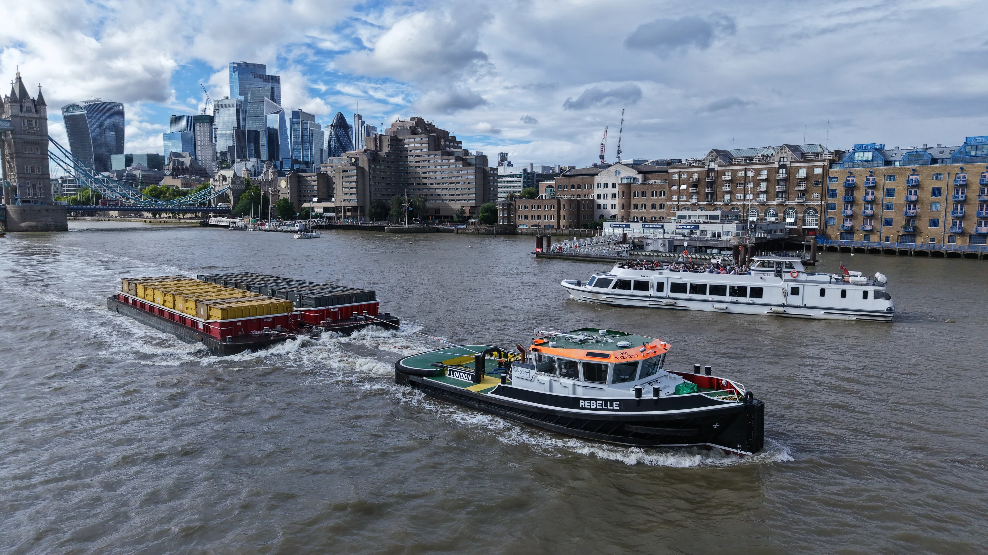 The Cory tug Rebelle under way in the Pool of London with a loaded waste container barge in tow