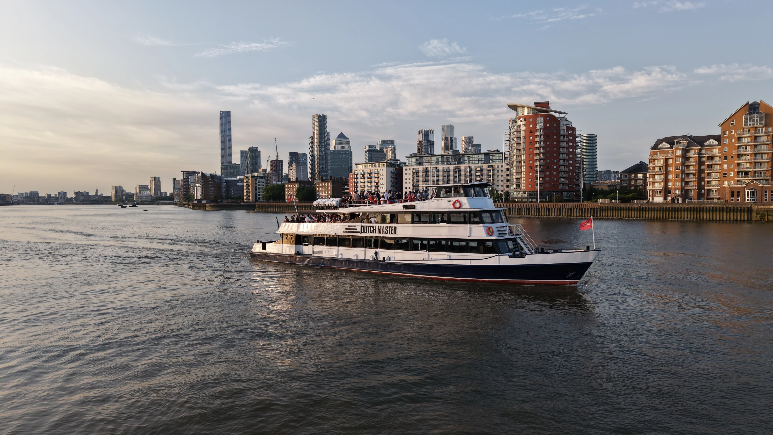 The Dutch Master under way on the Thames at Limehouse Reach in evening light, with the Canary Wharf towers on the skyline behind