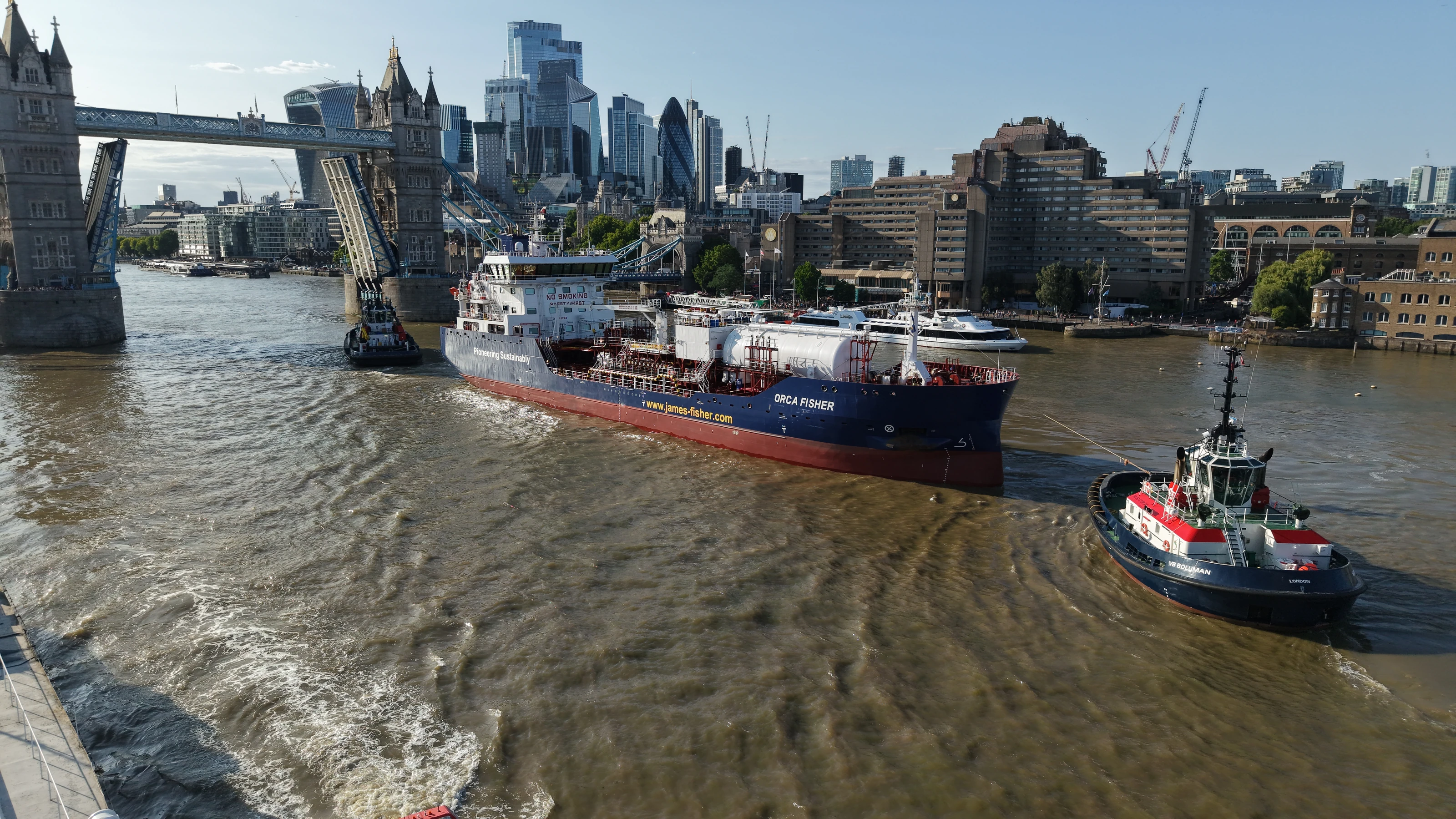 The Orca Fisher passing through Tower Bridge on the River Thames with Boluda tugs in attendance