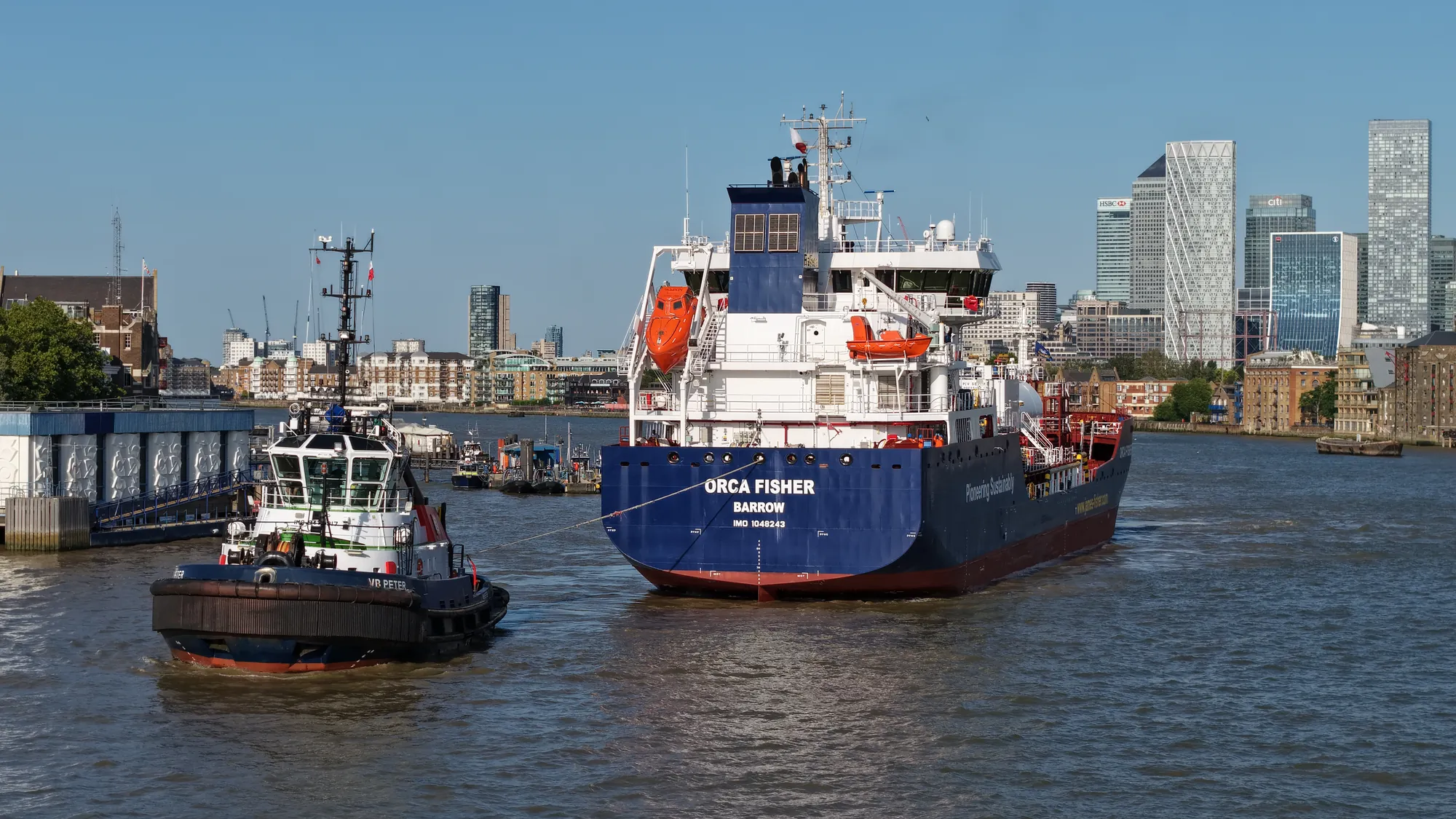Tanker Orca Fisher with a tug in attendance on the River Thames at Canary Wharf