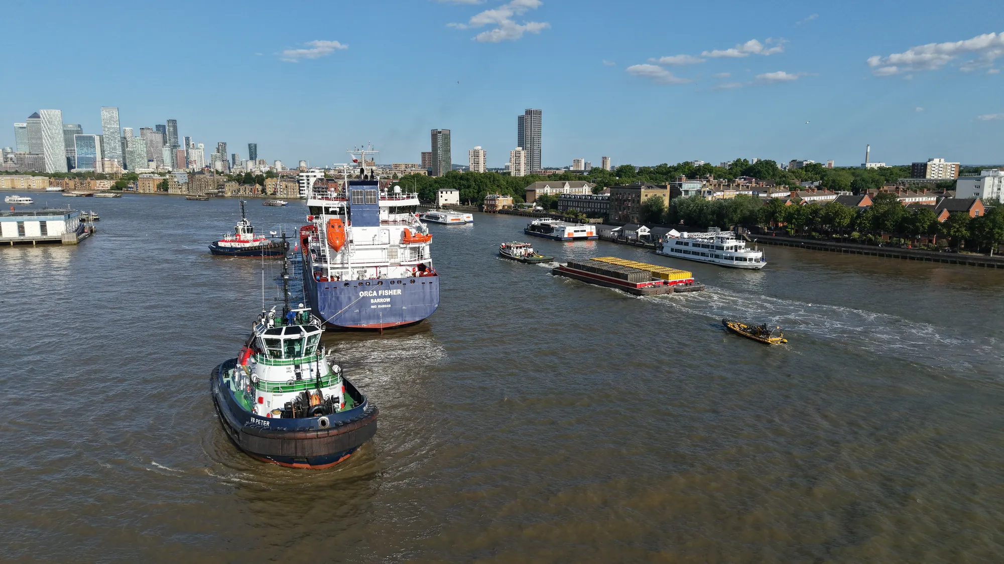 Aerial view of the Orca Fisher tanker under tug escort on the tidal River Thames, London