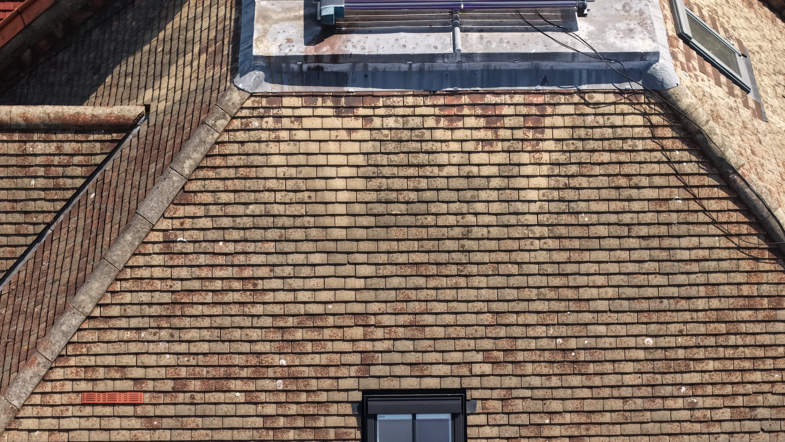 Close aerial view of a plain tile roof during a residential condition survey, tile courses and ridge line recorded square on.